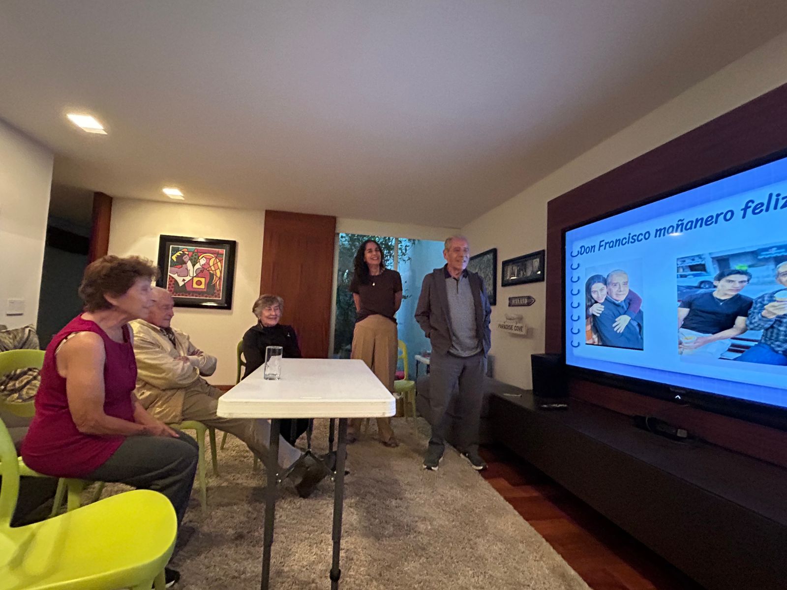 Grupo escuchando la presentación de un participante frente a una pantalla